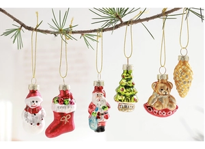 Detailed view of six painted glass Christmas ornaments hanging on natural pine branches