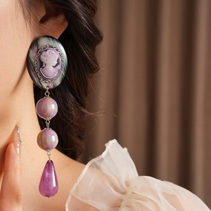 Close-up of vintage purple resin cameo teardrop earrings on a female model