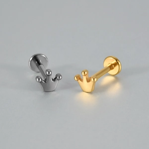 Détail rapproché de boucles d'oreilles en forme de couronne en finitions argent et or