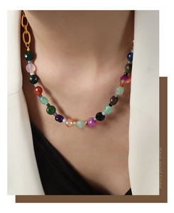 Vue macro des perles d'agate facettées et chaîne en titane doré sur blazer beige