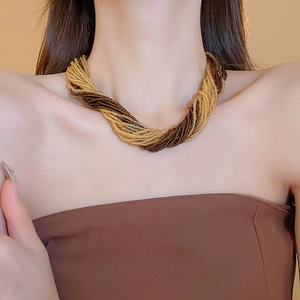 Dettaglio della collana di perline intrecciate multistrato oro e marrone su modella