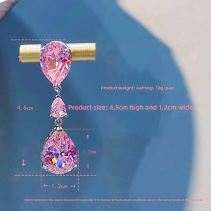 Macro view of pink pear-cut crystal teardrop earrings hanging on gold display stand