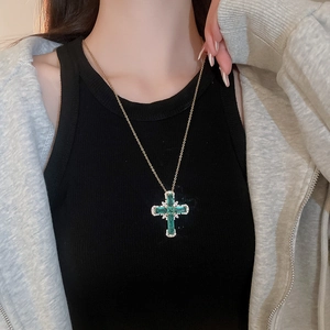 Détail du collier pendentif croix en cristal vert avec zircons brillants sur chaîne dorée