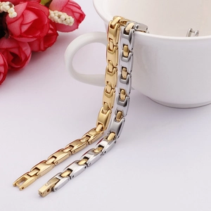 Close-up of minimalist H-link titanium steel bracelets in gold and silver on a white cup