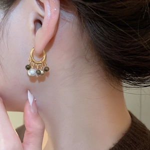 Close-up of 18k gold plated hoop earrings with white pearl and tiger eye stone beads