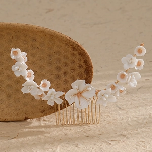Macro detail of white ceramic flower bridal hair comb with gold wires and metal teeth