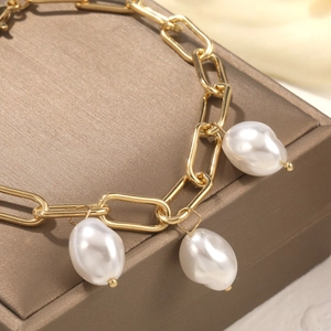 Detailed macro view of baroque pearls on a gold paperclip chain bracelet on silk
