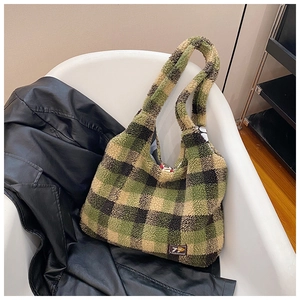 Detail of green plaid plush tote bag with 79 Fashion label on a white chair