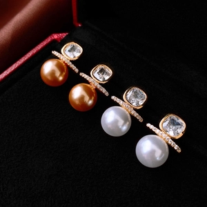 Elegant gold earrings set with square zircon and faux pearls on black velvet display