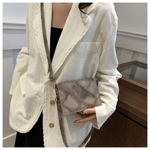 Dettaglio borsa a tracolla trapuntata talpa indossata con un blazer in tweed bianco