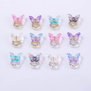 Macro view of colorful resin butterfly nail charms with rhinestone bases and aurora finish