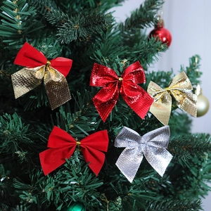 Mini velvet and glitter Christmas bows hanging on a green festive tree for holiday decor