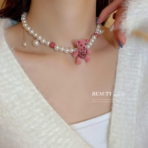 Pink flocked bear pearl necklace with rhinestones and gold accents on a fuzzy white top