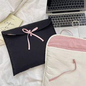 Custodie per laptop trapuntate con fiocchi rosa esposte su biancheria da letto bianca