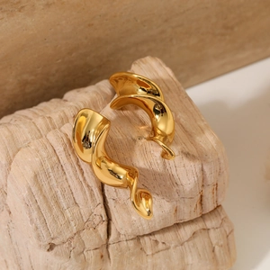 Close-up of golden spiral twist earrings displayed on natural stone with soft lighting