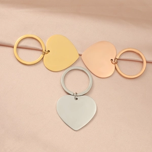 Detailed view of heart-shaped keychains in gold, silver, and rose gold on pink silk fabric