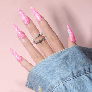 Macro shot of long stiletto press-on nails with pink glitter and colorful sequins detail