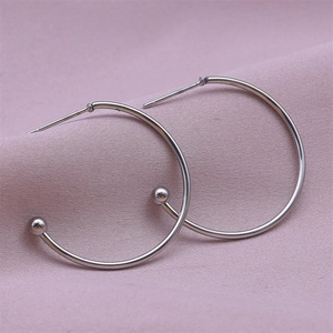 Close-up of silver stainless steel hoop earrings with bead detail on purple fabric