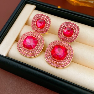 Detailed macro view of vintage square gold earrings with red stones and pink crystals