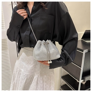 Detail of silver rhinestone bucket bag featuring metal chain and pearl drawstring tassels