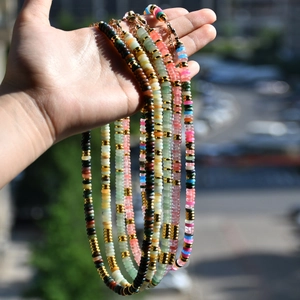 Détail d'un collier de pierres multicolores avec perles dorées et fermoir mousqueton