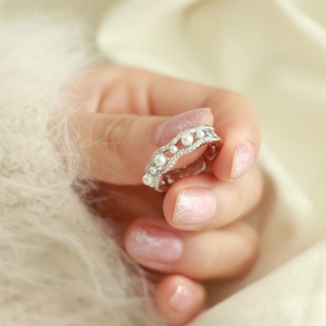 Macro detail of silver wavy ring featuring delicate pearls and sparkling diamond accents