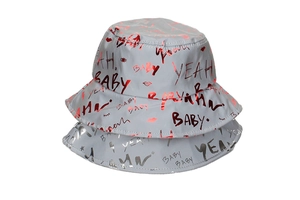 Detail of reflective graffiti print bucket hat with BABY and YEAH text patterns