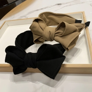 Detail of khaki and black layered bow headbands on a white tray with marble background