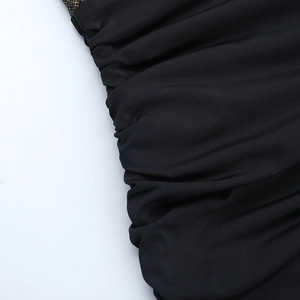 Detail of ruched black fabric with delicate mesh stitching on a mini evening dress