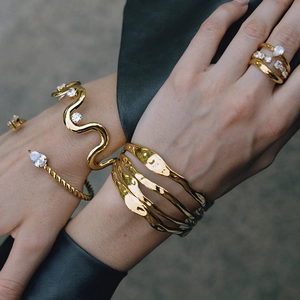 Close-up of stacked gold-tone stainless steel bangles and rings with zircon inlay