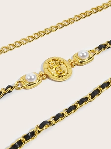 Detail of gold chain belt with black leather, vintage crown emblem and white pearls