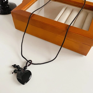Detail shot of heart-shaped obsidian-style pendant with black woven rope and beads