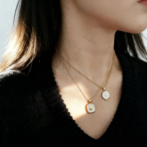 Collana a doppio strato dorata con ciondoli a cuore in smalto bianco su una modella