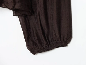 Detail of dark brown chiffon sleeve with pleated texture and elastic cuff finish