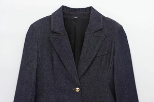 Detailed view of dark blue denim blazer with gold metal button and sharp lapel collar