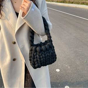 Detail of a handmade black chunky knit handbag featuring unique woven texture for women
