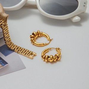 Detailed view of gold multi-layer coil hoop earrings on a stylist desktop background