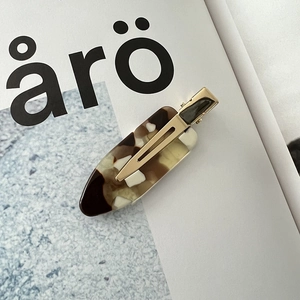 Detail of amber tortoiseshell acetate hair clip with polished gold metal fastener