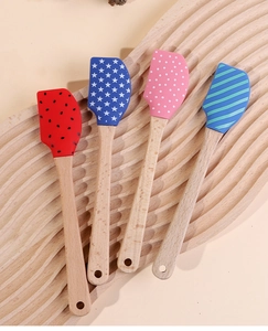 Detail of Christmas silicone spatulas with patterned heads and wooden handles on a tray