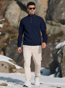 Detail of navy knit sweater featuring elbow patches and buttoned stand collar in the snow