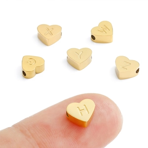 Detailed macro shot of heart-shaped gold stainless steel alphabet beads for DIY jewelry