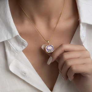 Detailed macro view of a vintage rose oil painting pendant with fine golden chain necklace