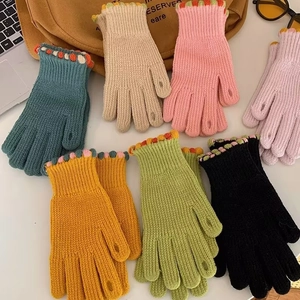 Dettaglio guanti in maglia colorati con punte aperte e polsini decorati a pois