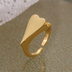 Detalle de un anillo de sello de corazón dorado minimalista con banda abierta ajustable