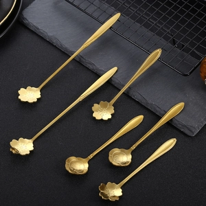 Set of 6 gold stainless steel spoons with floral and rose shaped heads on black background