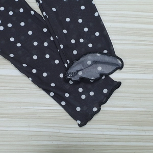 Close-up of black mesh sleeves with white polka dots and delicate ruffle edge detail