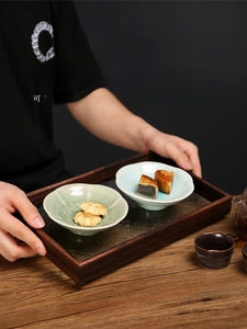 Detail of dark wood tray with embossed base and celadon petal ceramic bowls