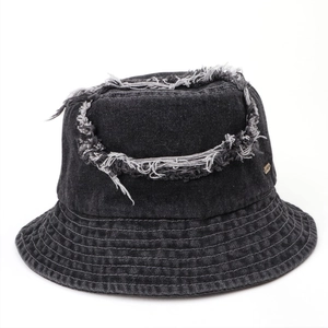 Detail of frayed edge crown and metal logo on vintage black denim bucket hat