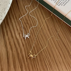 Detailed view of silver and gold bow pendants on a rustic wooden surface with book accents