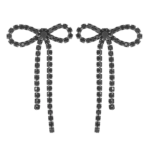 Macro detail of elegant black rhinestone bow earrings with shimmering tassel chains
